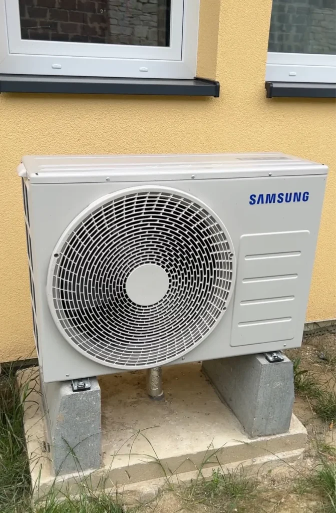 Mikołów - Zewnętrzna jednostka pompy ciepła Samsung zainstalowana przed budynkiem.